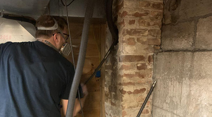 A chimney technician inspecting visible cracks and spalling brickwork on a St. Louis home chimney